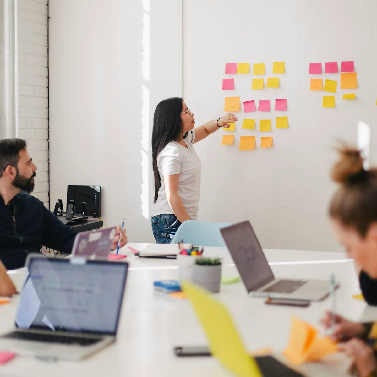 Atelier en groupe : une animatrice organise des notes au mur pendant que les participants travaillent sur leurs ordinateurs.